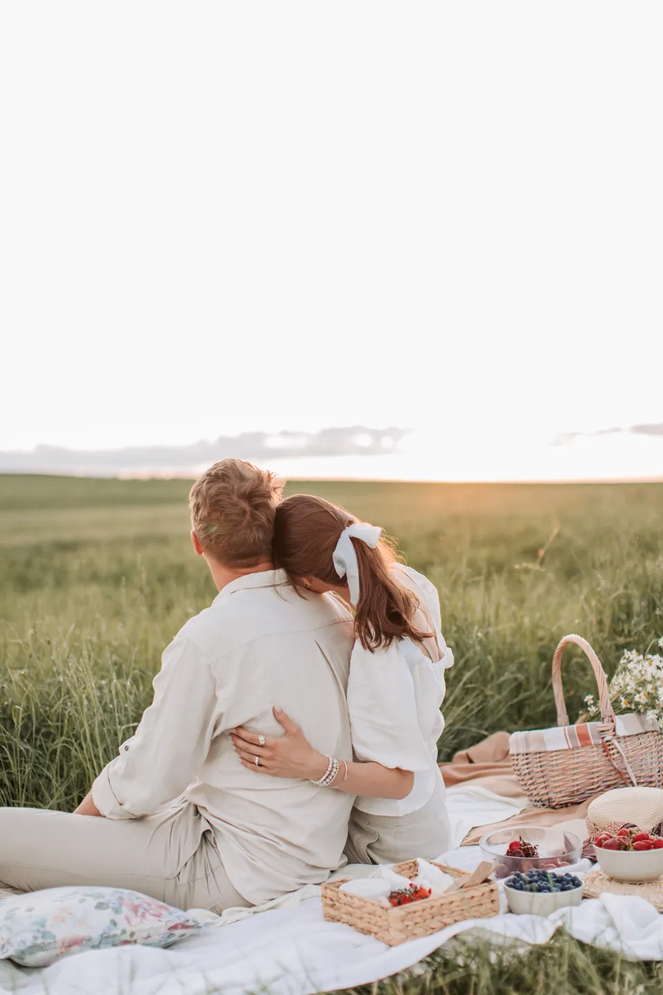 A couple sitting together at a picnic in a sunlit field.